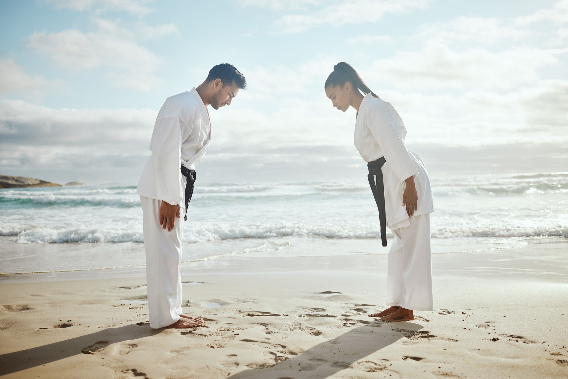 Full length shot of two young martial artists practicing karate on the beach